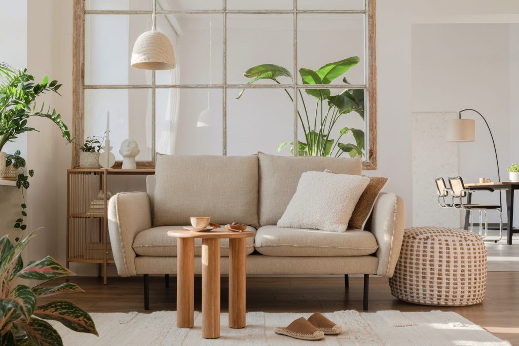 Elegant living room interior design with beige modern sofa, side table and creative accessories. Template. Copy space. Dining room in the background.